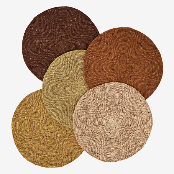 Set of five round woven seagrass placemats in various earthy tones