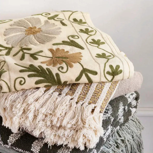 Stack of decorative blankets with embroidered Suzani patterns