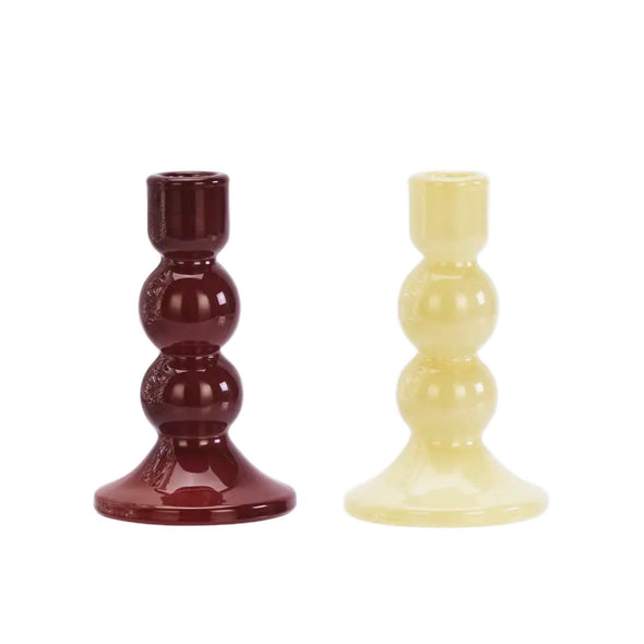 Two glass candle holders, one red and one yellow