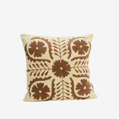 Decorative pillow with brown floral pattern on an off white base