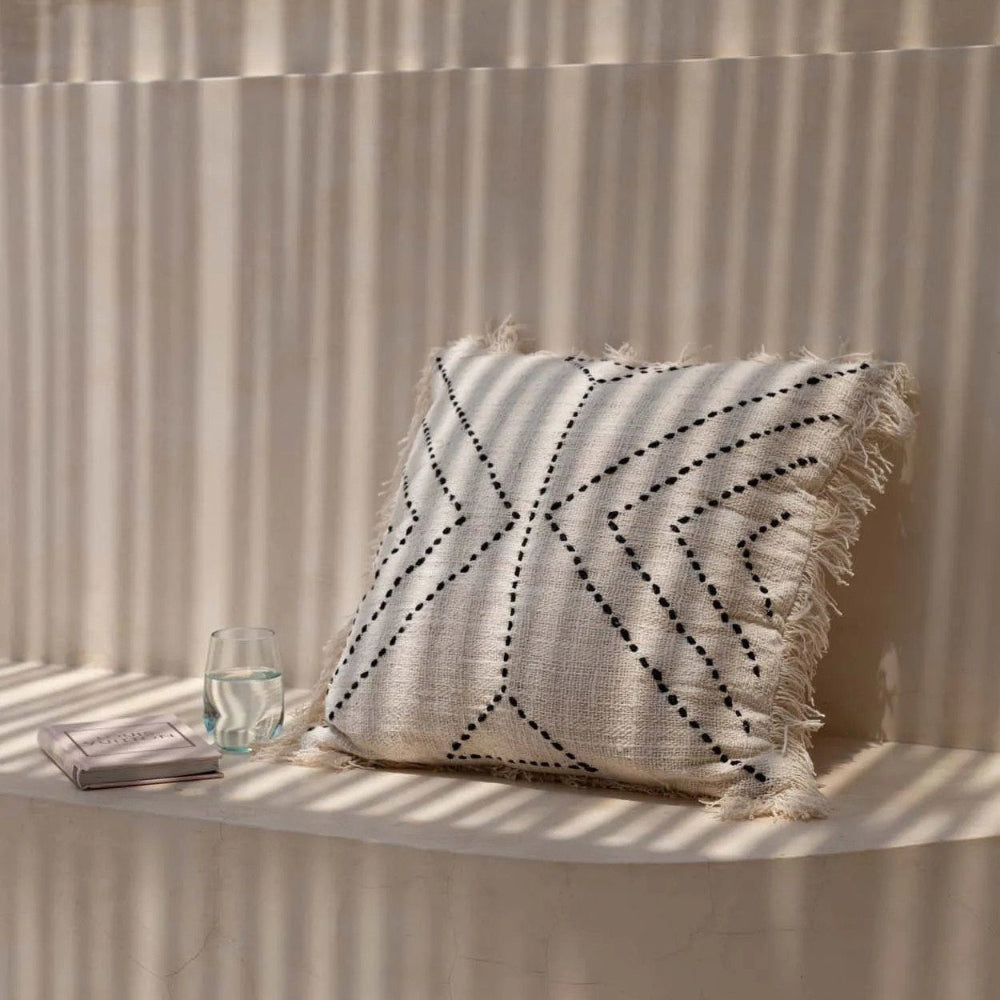 Decorative pillow with geometric pattern on a sunlit wall