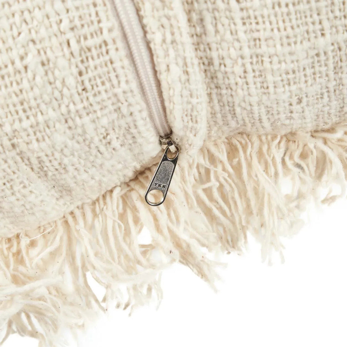 Close-up of a textured beige fabric with a zipper and fringes.