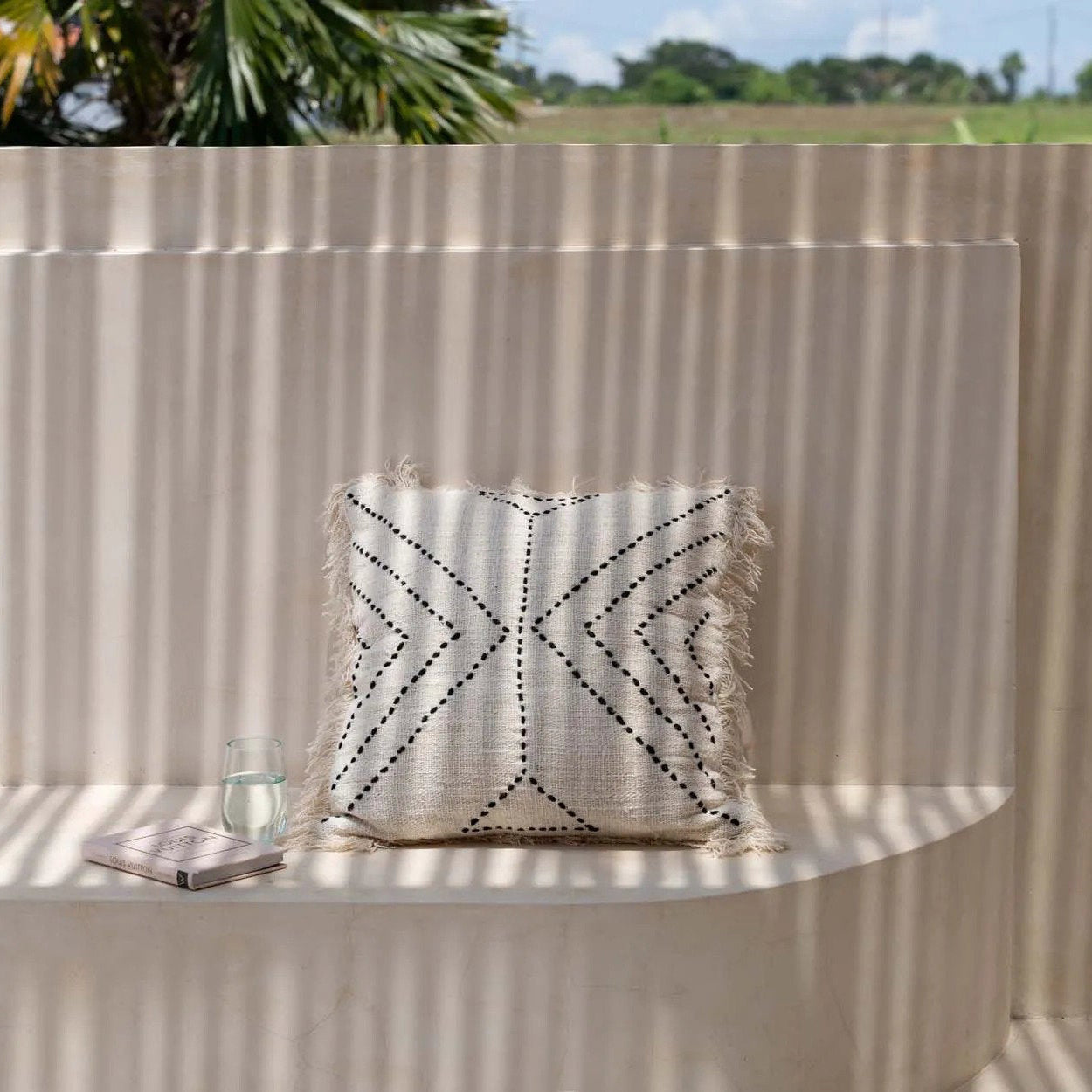 Decorative pillow with geometric pattern on a stone ledge outdoors