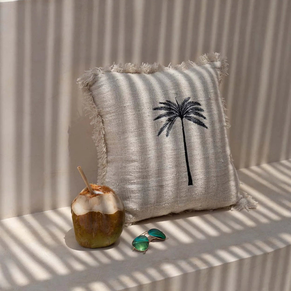 Decorative pillow with palm tree design with coconut and sunglasses.
