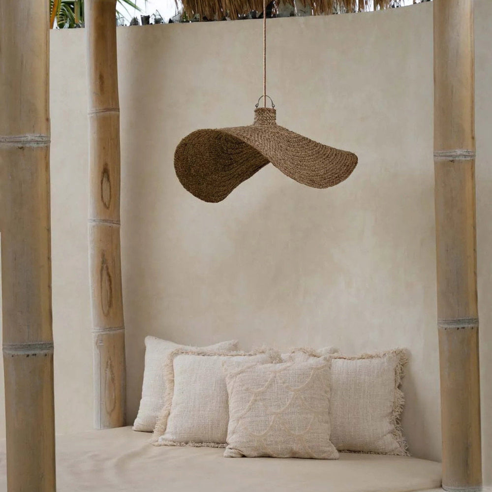 Nestled corner with a thatched roof, cushioned seat, and woven hat hanging above.