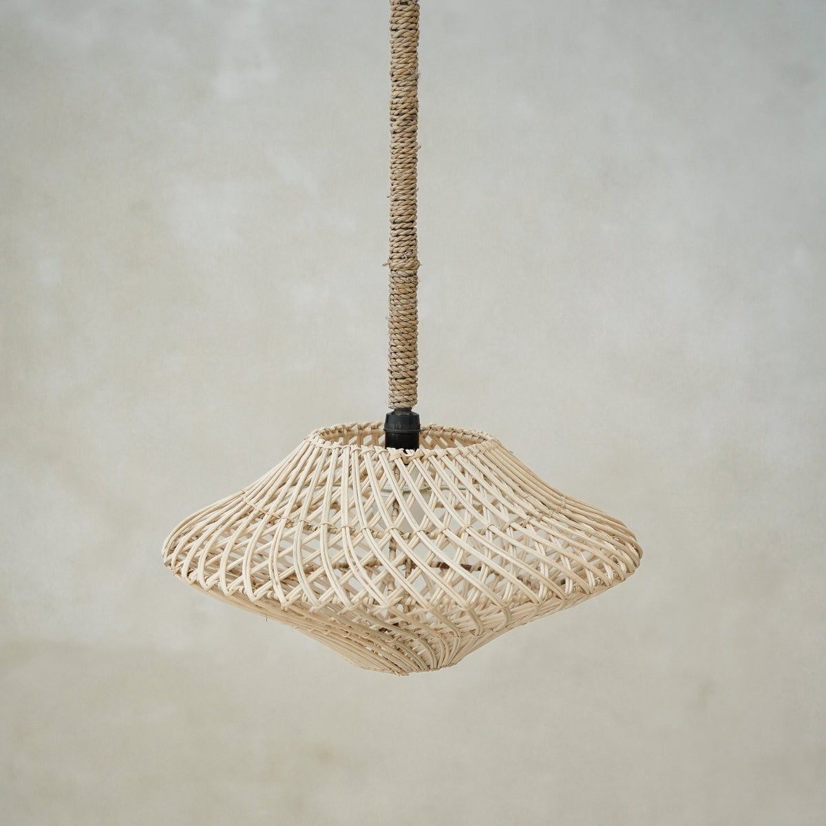 Woven pendant light hanging against a plain background
