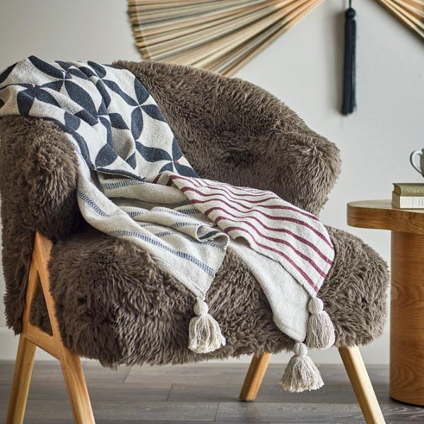 Brown armchair with patterned blanket and wooden side table in a room setting