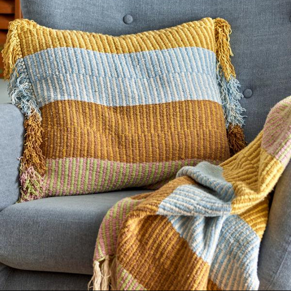 Textured pillow with fringes on a gray sofa