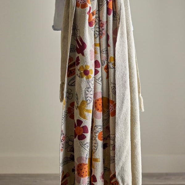 Person holding a floral-patterned blanket with tassels