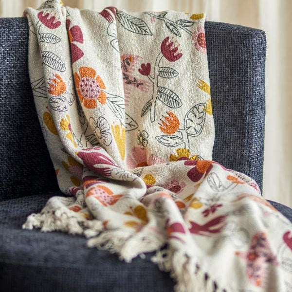 Floral patterned blanket draped over a dark blue armchair Bloomingville