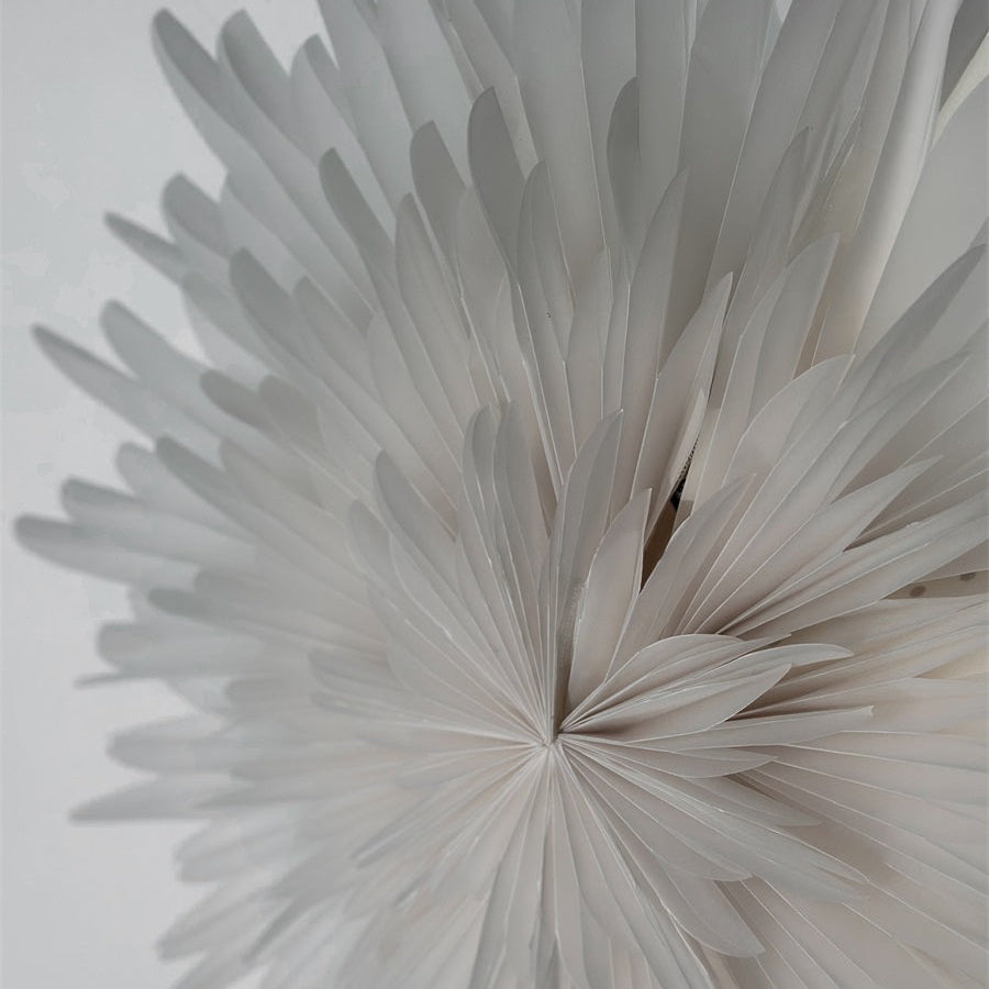 A close-up of a white paper flower or paper lantern-style decorative object made of many layered paper petals