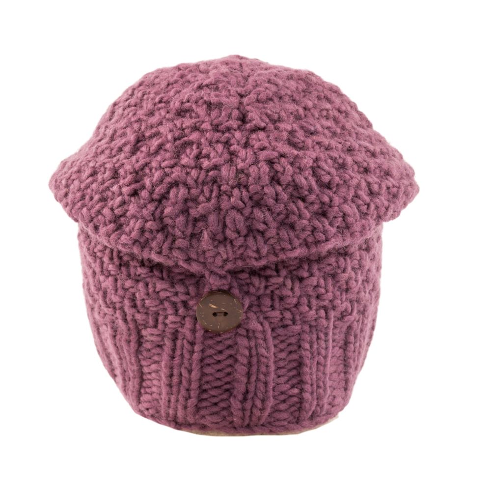 A dusty rose pink chunky knit beanie hat with a brown button closure on the front