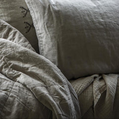 Close-up of textured pillows and vintage quilt blanket in linen colour