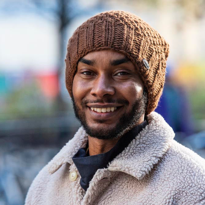 A smiling man wearing a brown cable-knit beanie by KuSan