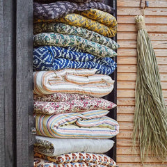 Stack of sustainable cotton mattress cushions in assorted prints and colours on terrace
