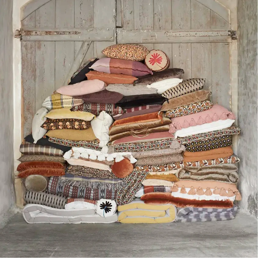 Stack of patterned cushions against a rustic wooden door.