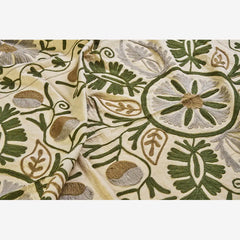 Embroidered fabric with green and grey floral patterns on a beige background