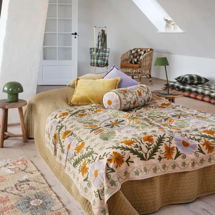 Bedroom with floral quilt and colourful cushions on a bed