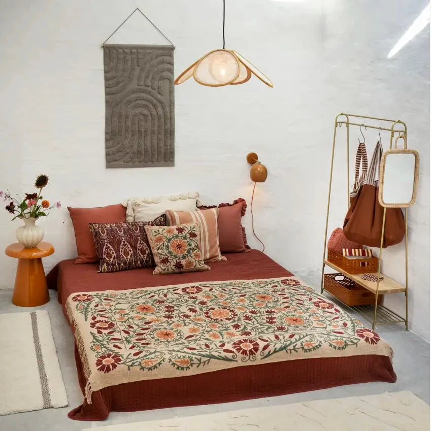 Bedroom with floral bedspread, pillows, and a coat rack with bags.