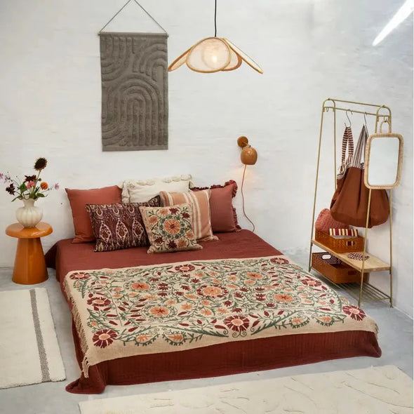 Bedroom with floral bedspread, pillows, and a coat rack with bags.