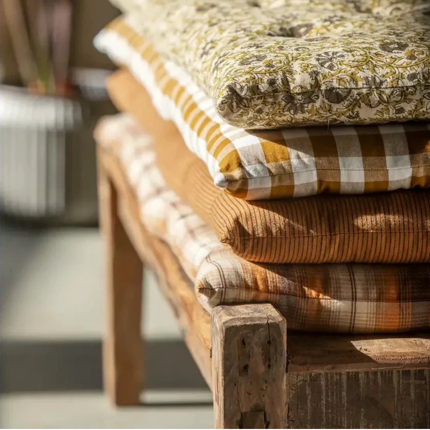 Stack of bench cushions on a wooden bench by Madam Stoltz