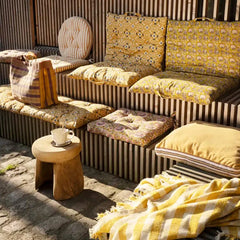 Outdoor seating area with striped bench, cushioned chairs, and a small table.