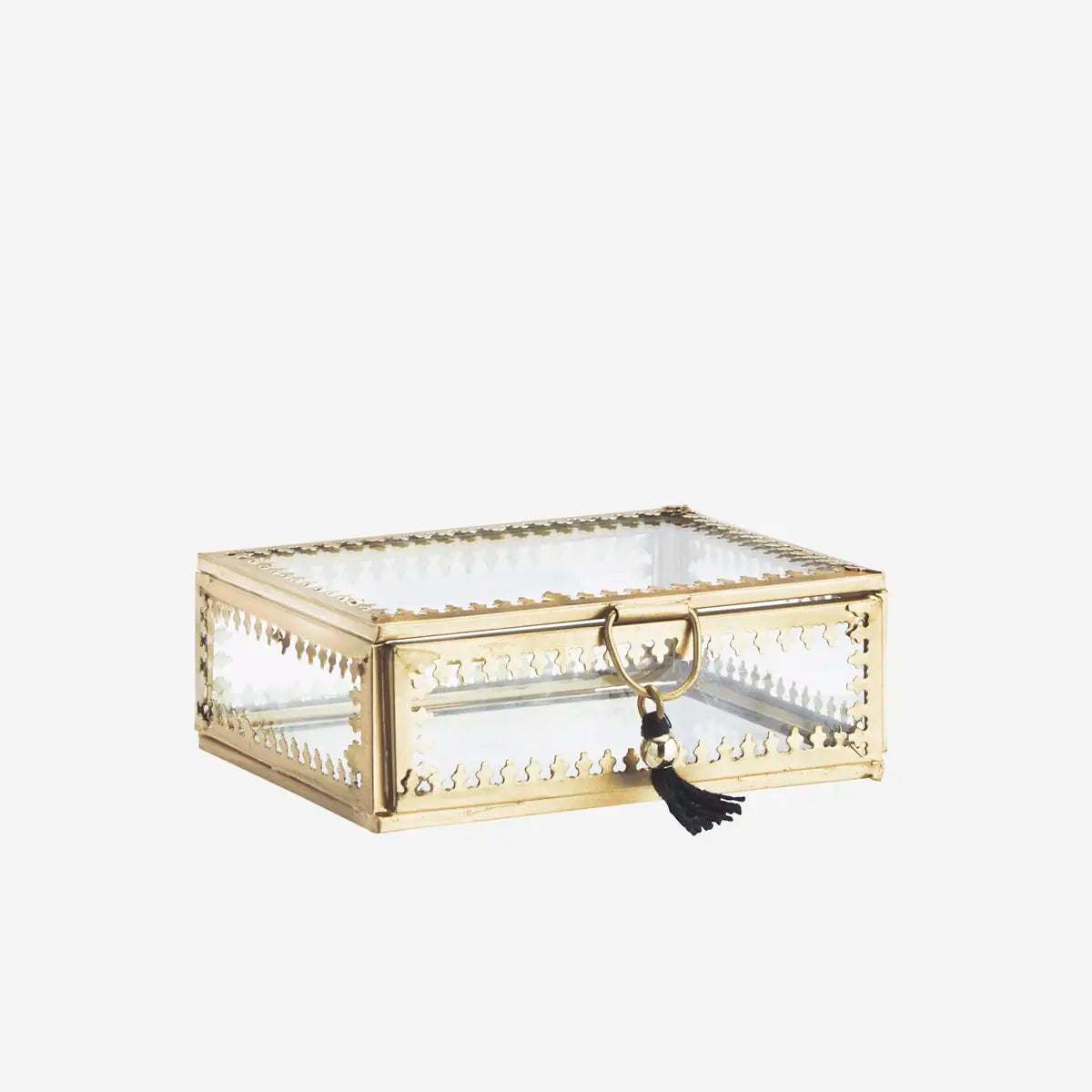 A rectangular gold-toned jewelry box with a clear glass top and sides, decorative cutout detailing, a gold clasp, and a black tassel charm
