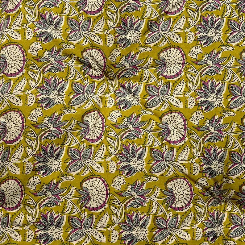 A close-up of a Madam Stoltz mattress cushion featuring a repeating design of stylized leaves and semi-circular floral motifs in olive yellow, cream, gray, and burgundy.