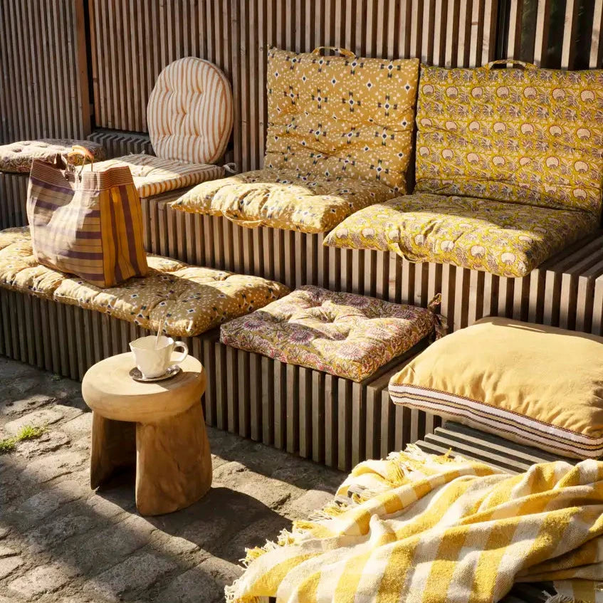 Outdoor seating area with striped bench, cushioned chairs, and a small table.