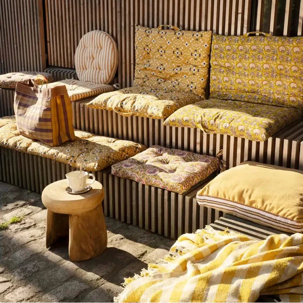 Outdoor seating area with striped bench, cushioned chairs, and a small table.