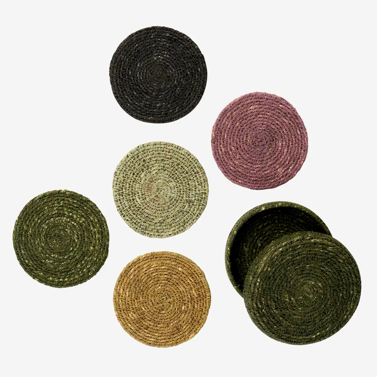 Six round woven seagrass coasters in various earthy colours including black, olive green, mustard yellow, and dusty rose