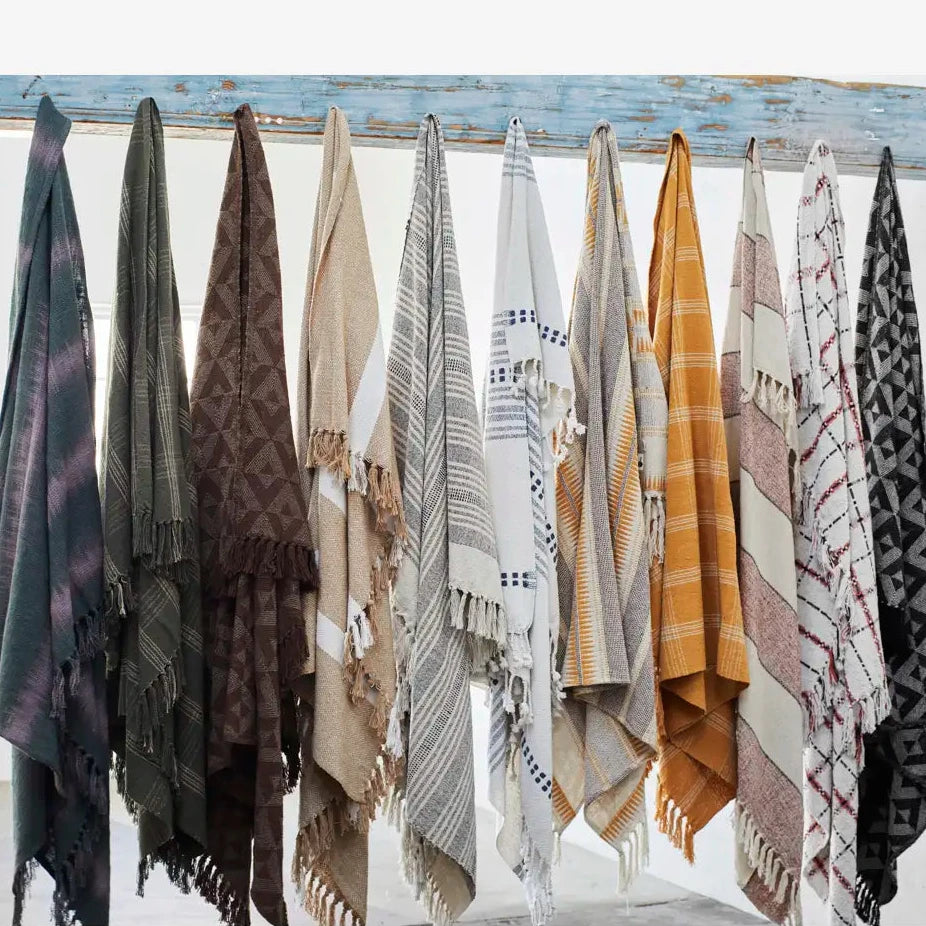 A row of woven throw blankets and shawls in assorted colours and patterns