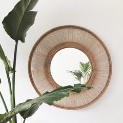 Round woven mirror with a plant 