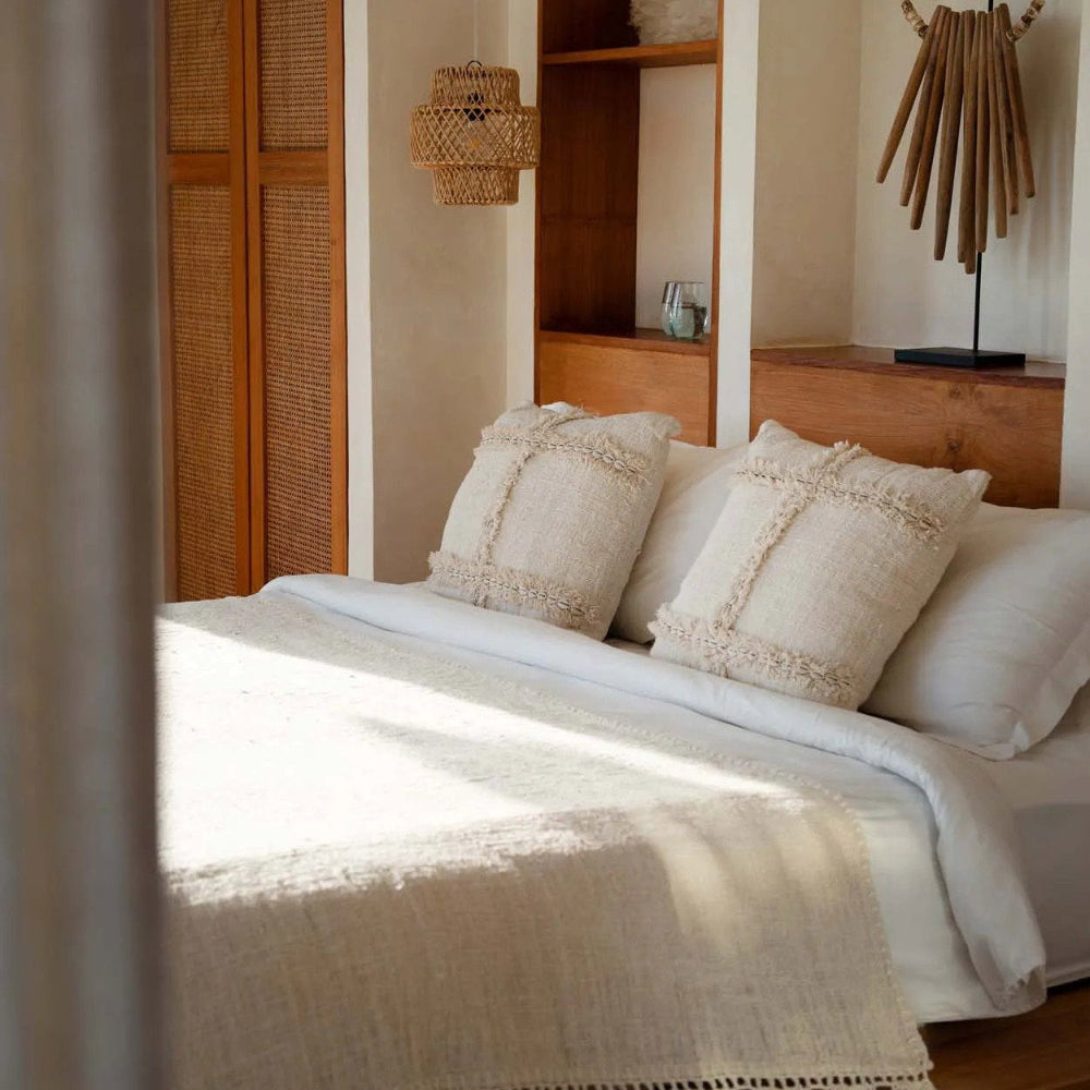Bedroom with wooden headboard, white bedding, and decorative cushions