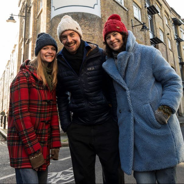 three people wearing woolly cable bobble hats
