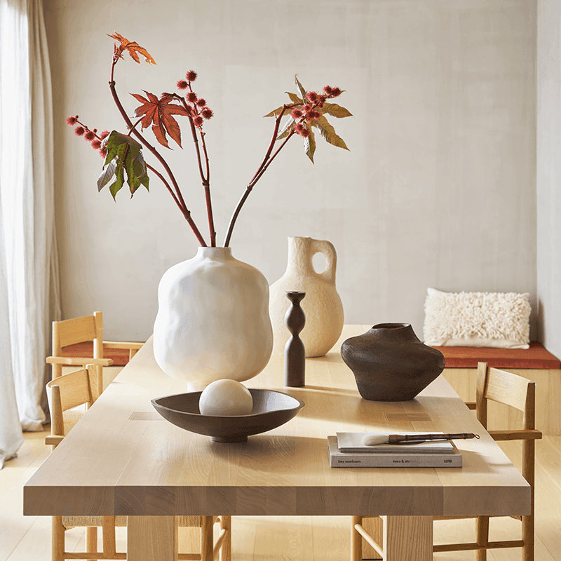 Decorative setting with vases and flowers on a table in a room.