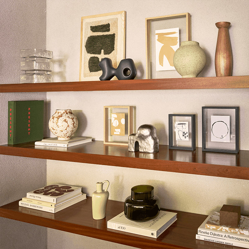 Wooden shelves with decorative items including books, vases, and sculptures against a neutral wall.