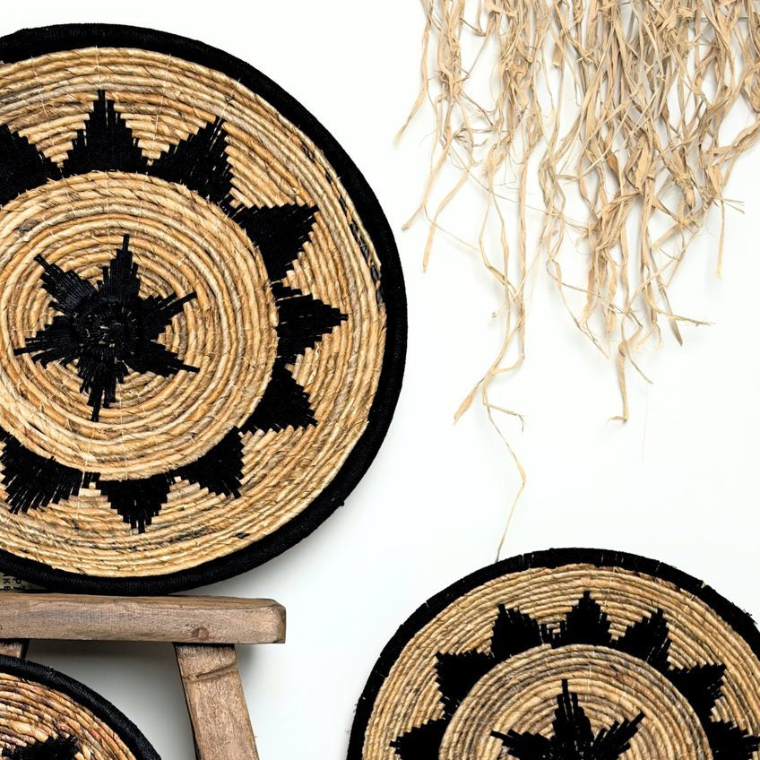 Three woven wall baskets with black star patterns on a white surface.