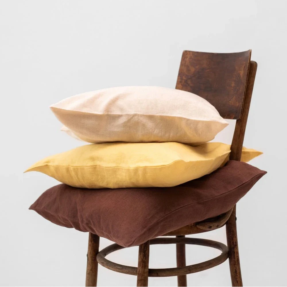 Three linnen cushions stacked on a wooden chair