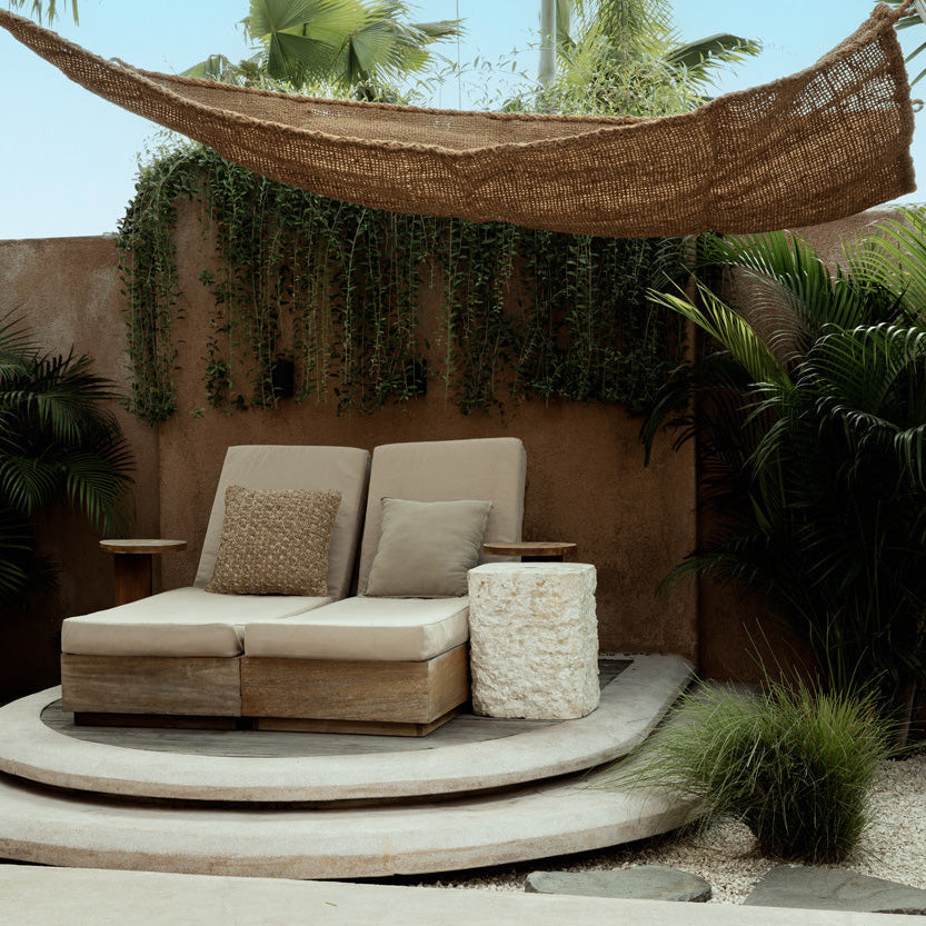 Outdoor seating area with a hammock, couch, and plants in a tropical setting.