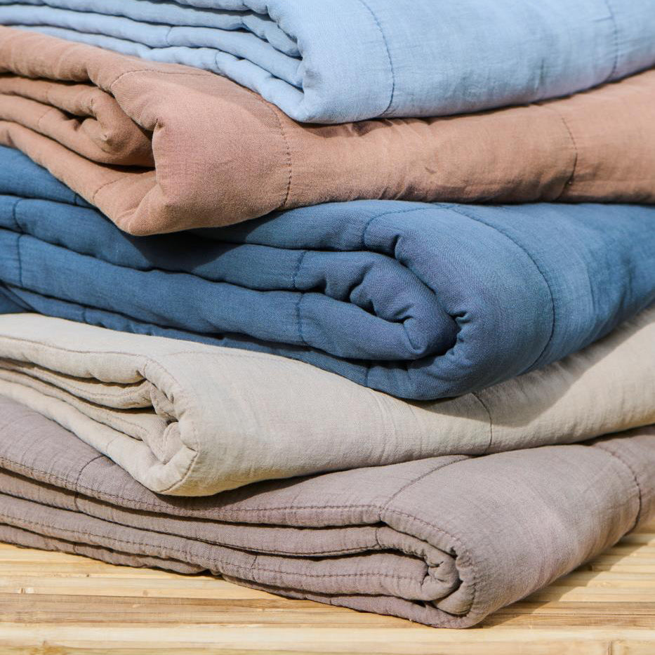 Stack of folded quilt blankets in various colours