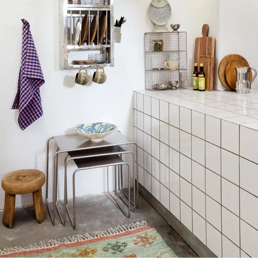 Modern kitchen with white tiled walls, wooden stool