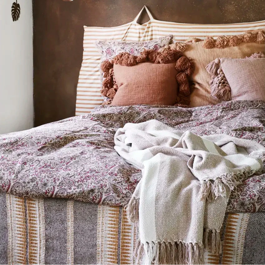 Bedroom with a bed featuring patterned bedding and pillows, and a textured wall.
