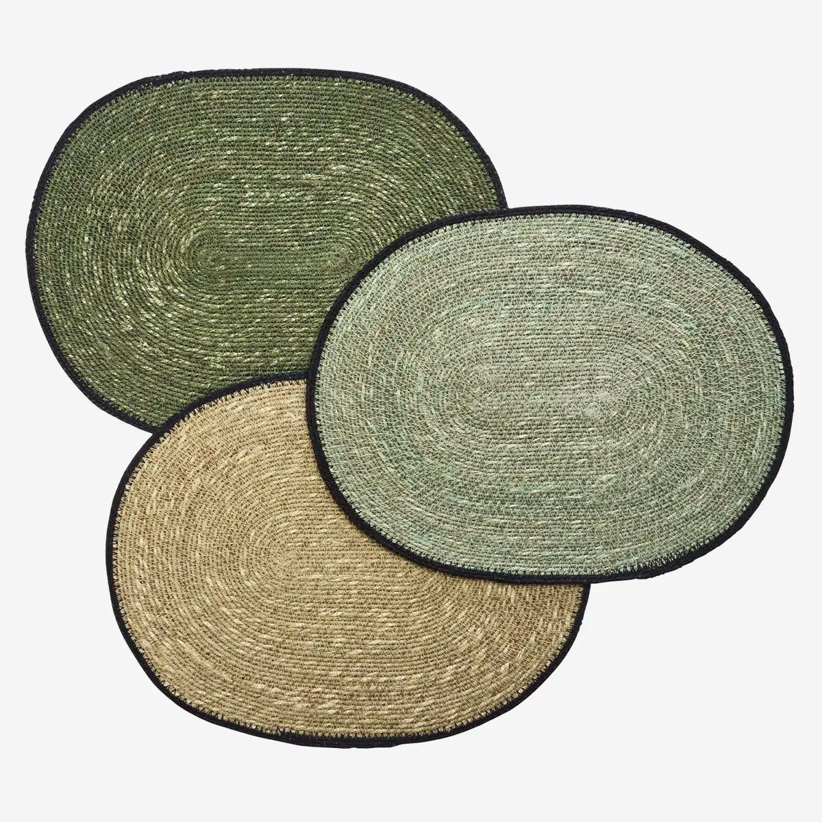 Three round woven seagrass placemats in green, beige, and brown with a black border