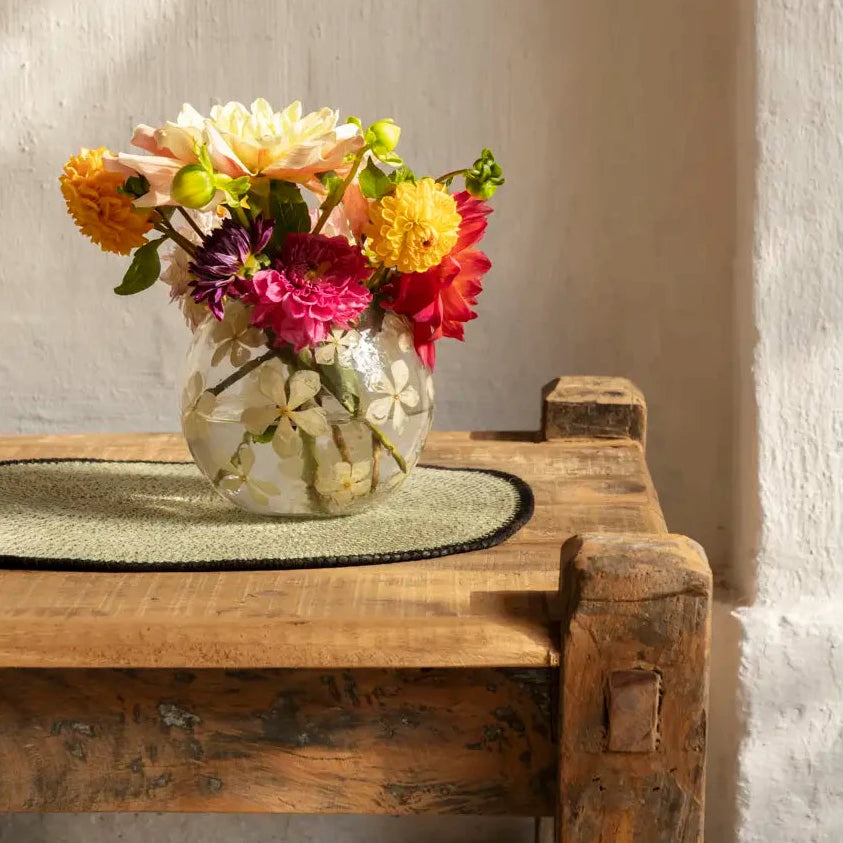 Vase with flowers on a wooden table with seagrass placemat 