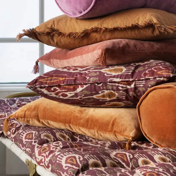 Stack of colourful boho style cushions in trend colours autumn 2025