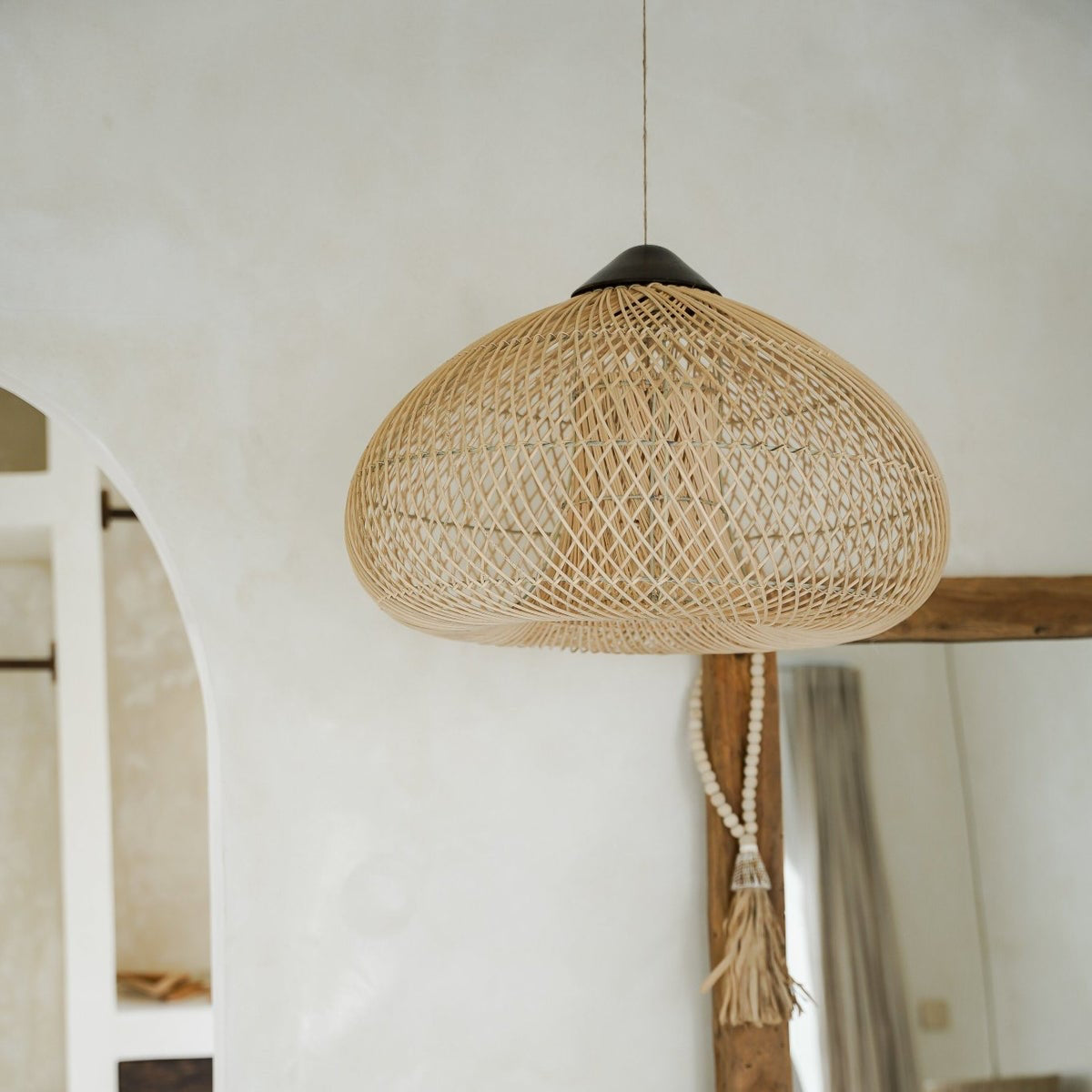 Woven pendant light hanging in a room with neutral decor