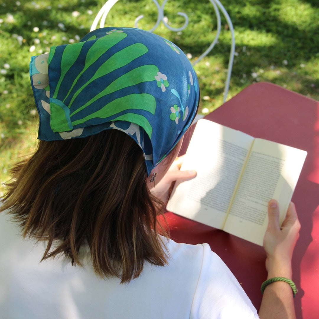 Person reading a book outdoors with a colourful headscarf