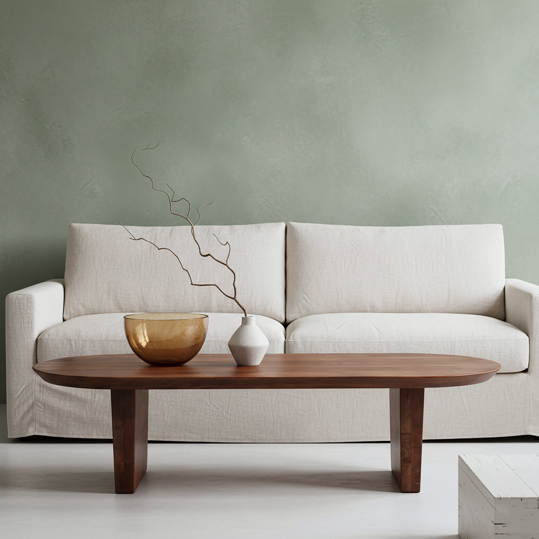 Beige sofa with a wooden coffee table and decorative items against a green wall.