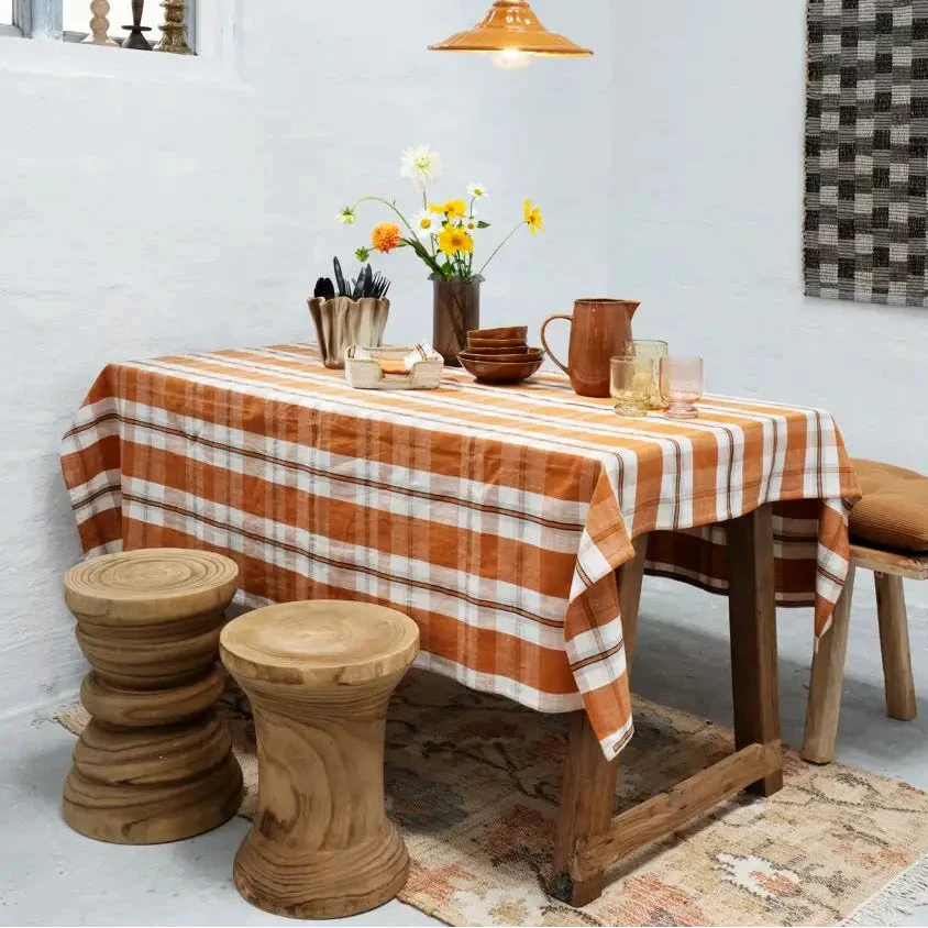 Dining room with wooden table and chairs, plaid tablecloth, and decorative elements.